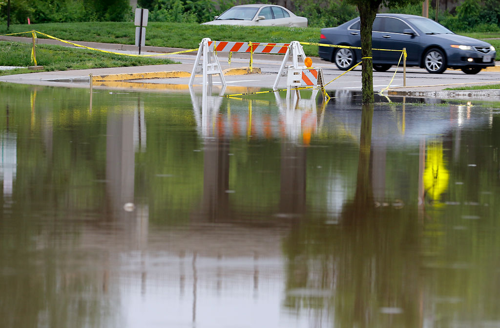 A car drives past a halfway flooded parking lot near the Missouri State Capitol Building
